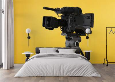 Modern professional video camera on yellow background Wall mural