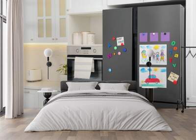 Modern refrigerator with child's drawings, notes and magnets in kitchen. Space for text Wall mural