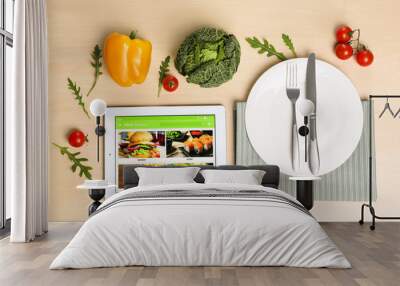 Modern tablet with open page for online food ordering, vegetables, spices, plate and cutlery on wooden table, flat lay. Concept of delivery service Wall mural