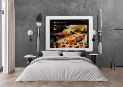 Modern tablet with open page for online food ordering and cutlery on black table, flat lay. Concept of delivery service Wall mural