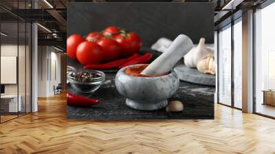 Mortar with red curry paste and ingredients on black textured table Wall mural