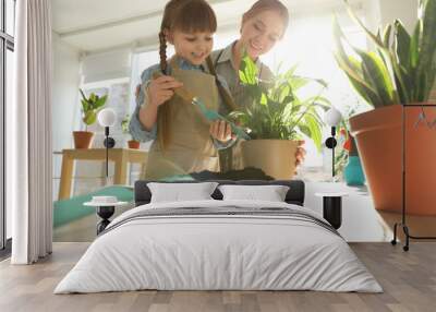 Mother and daughter taking care of home plants at table indoors Wall mural