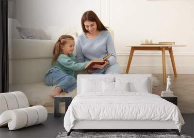 Mother and her daughter reading book at home. Floor heating concept Wall mural