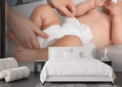 Mother changing baby's diaper on bed, closeup Wall mural