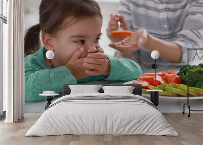 Mother feeding her daughter indoors, closeup. Little girl refusing to eat vegetables Wall mural