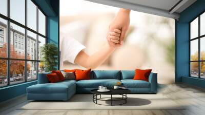 Mother holding hands with her child indoors, closeup. Happy family Wall mural