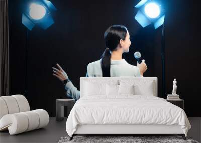 Motivational speaker with microphone performing on stage, back view Wall mural