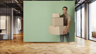 Moving into new house. Man with cardboard boxes on light green background, space for text Wall mural