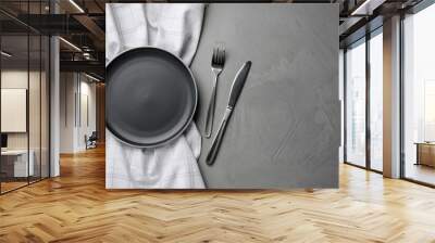 New dark plate, cutlery and napkin on grey table, flat lay. Space for text Wall mural