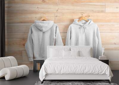 New hoodie sweaters with hangers on wooden wall. Mockup for design Wall mural