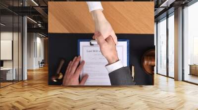 Notary shaking hands with client at wooden table, top view Wall mural