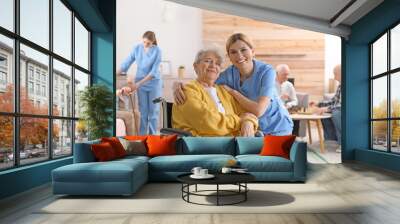 Nurse with elderly woman in wheelchair at retirement home. Assisting senior people Wall mural