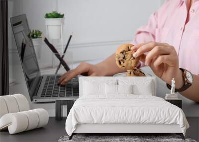 Office worker taking chocolate chip cookie from jar at workplace, closeup Wall mural