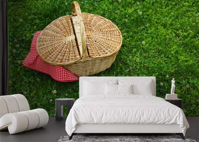 One picnic wicker basket with checkered napkin on green grass. Space for text Wall mural