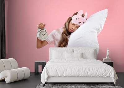 Overslept girl with sleep mask, pillow and alarm clock on pink background Wall mural