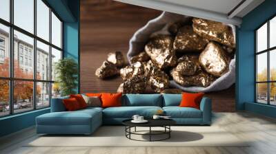 Overturned sack of gold nuggets on wooden table, closeup Wall mural