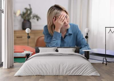 Overwhelmed woman sitting at table with documents in office Wall mural