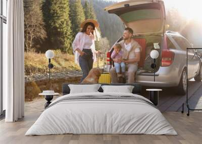 Parents, their daughter and dog near car outdoors. Family traveling with pet Wall mural