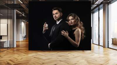 Passionate woman and handsome man using perfume on black background Wall mural