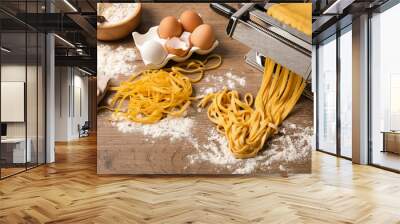 Pasta maker machine with dough and products on wooden table, above view Wall mural