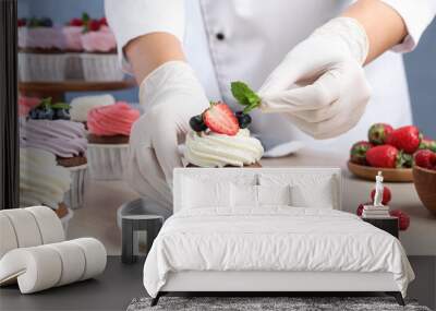 pastry chef decorating sweet cupcake with mint at light wooden table, closeup Wall mural