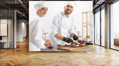 Pastry chefs preparing desserts at table in kitchen Wall mural