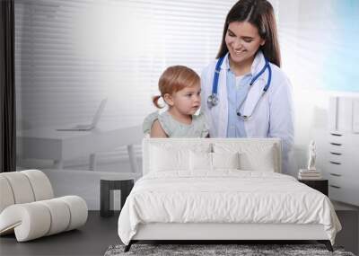 Pediatrician examining cute little baby in clinic Wall mural