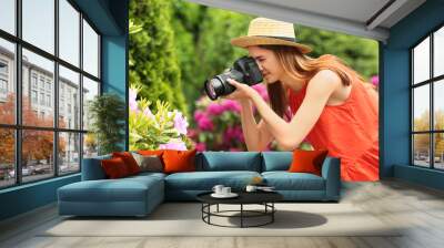 Photographer taking photo of blossoming bush with professional camera in park Wall mural