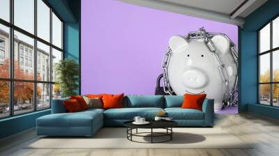 Piggy bank  with steel chain and padlock on lilac background, space for text. Money safety concept Wall mural