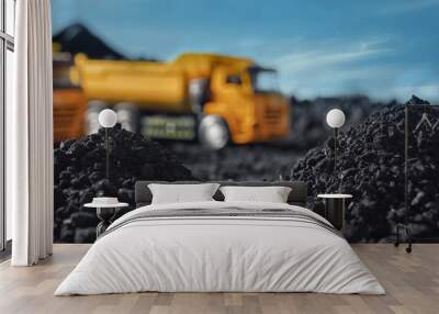 Pile of coal and blurred yellow truck on background, closeup Wall mural