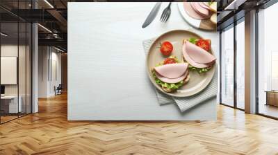 Plate of tasty sandwiches with boiled sausage, tomato and lettuce on white wooden table, flat lay. Space for text Wall mural