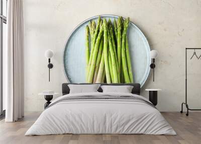 Plate with fresh green asparagus stems on light textured table, top view Wall mural