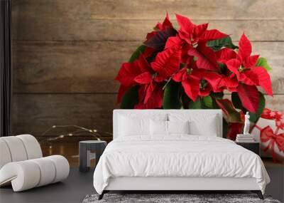 Poinsettia (traditional Christmas flower), string lights and gift boxes on wooden table. Space for text Wall mural