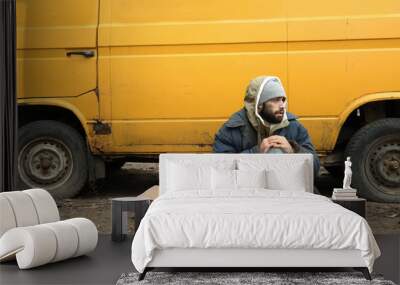 Poor homeless man sitting near van outdoors Wall mural