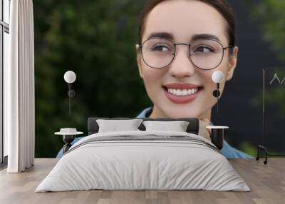 Portrait of beautiful woman in glasses on blurred background. Attractive lady smiling and posing for camera Wall mural