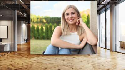 Portrait of beautiful woman sitting near house in yard, space for text Wall mural