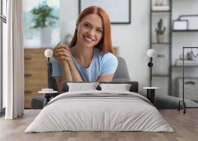 Portrait of beautiful young woman with red hair at home. Attractive lady smiling and looking into camera. Space for text Wall mural