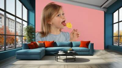 Portrait of cute girl licking lollipop on pink background, space for text Wall mural