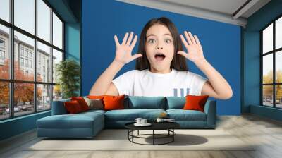 Portrait of cute little girl on blue background Wall mural