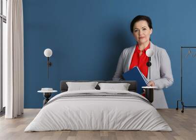 Portrait of female teacher with notebooks on color background Wall mural