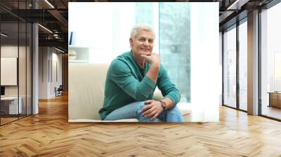 Portrait of handsome mature man on sofa indoors Wall mural