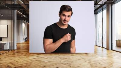 Portrait of handsome young man in black t-shirt on grey background Wall mural