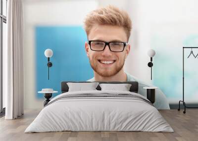 Portrait of handsome young man with glasses in room Wall mural