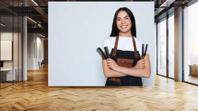 Portrait of happy hairdresser with professional combs on light background, space for text Wall mural