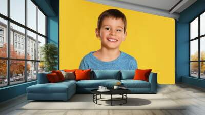 Portrait of happy little boy on yellow background Wall mural