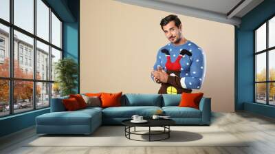 Portrait of happy man in Christmas sweater on beige background Wall mural