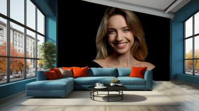 Portrait of happy young woman with beautiful blonde hair and charming smile on black background Wall mural