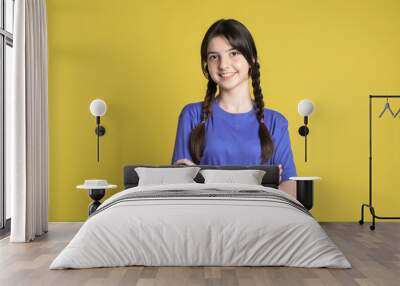 Portrait of smiling teenage girl on yellow background Wall mural