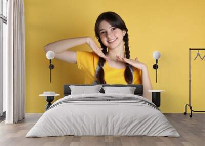 Portrait of smiling teenage girl on yellow background Wall mural