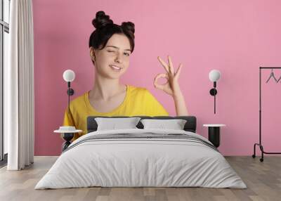 Portrait of smiling teenage girl showing ok gesture on pink background. Space for text Wall mural